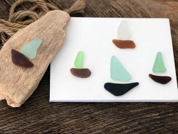 Hand holding a sea glass piece, with ocean and sky in background.