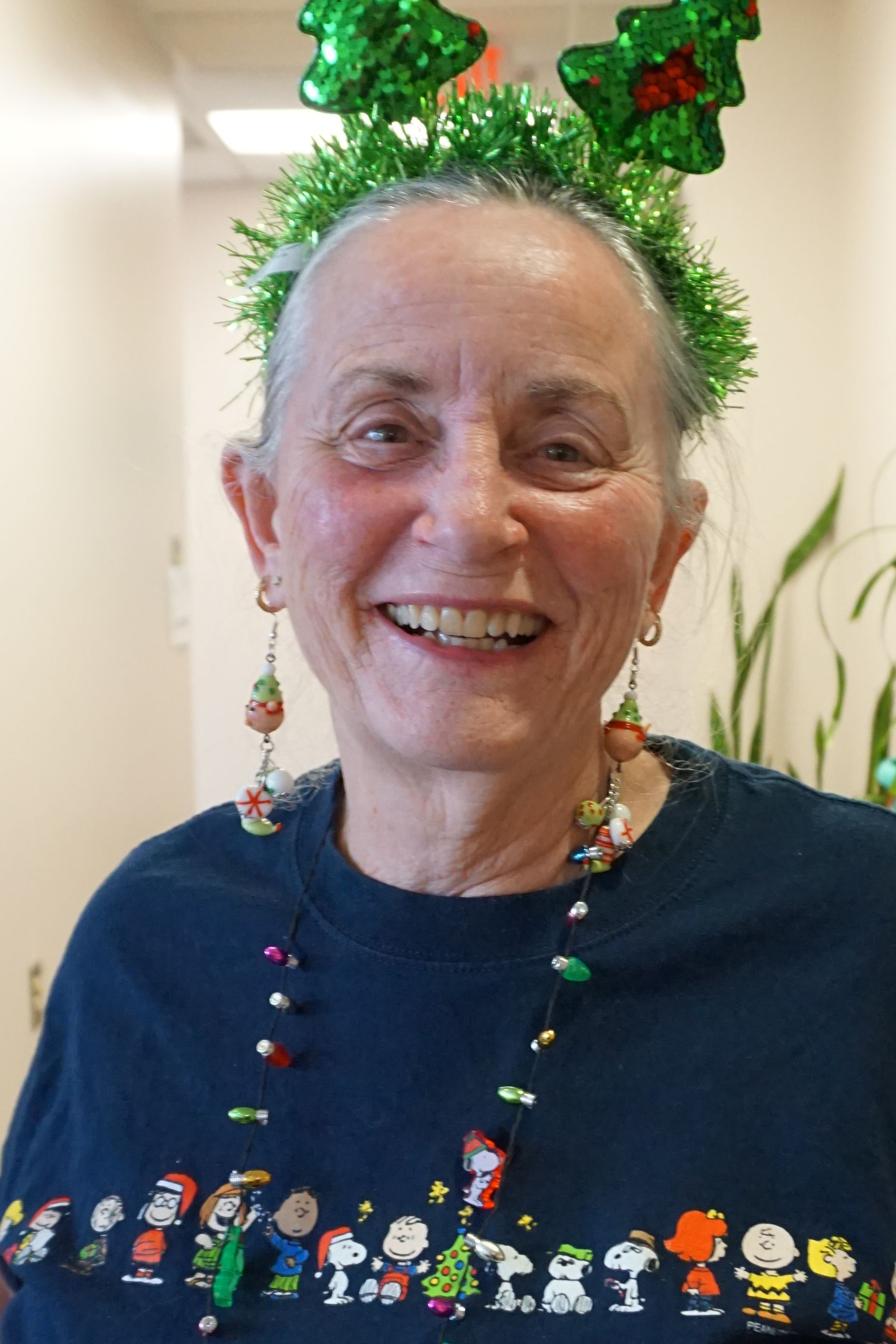 A woman wearing a peanuts sweater and a christmas headband
