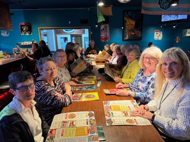 A group of people are sitting at tables in a restaurant looking at menus.