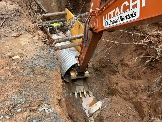 A hitachi excavator is digging a hole in the ground.