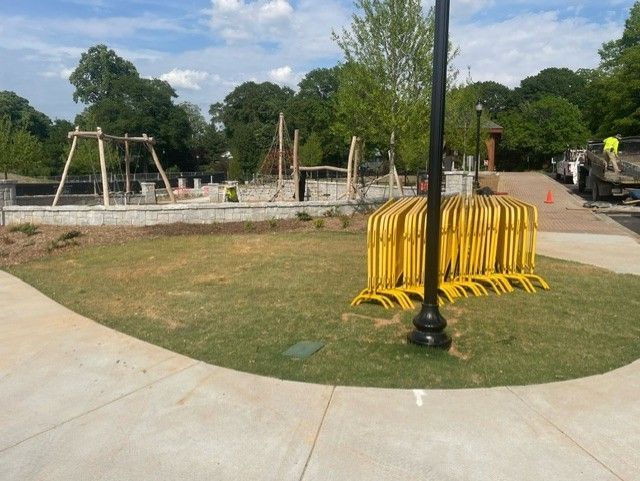 A playground is being built in a park with a lot of yellow barriers