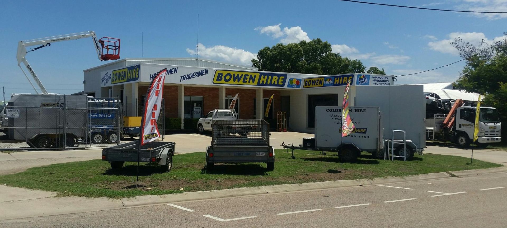 Boneyard event tent with display trucks and equipment in a grassy outdoor lot under a blue sky — Bowen Hire in Bowen, QLD