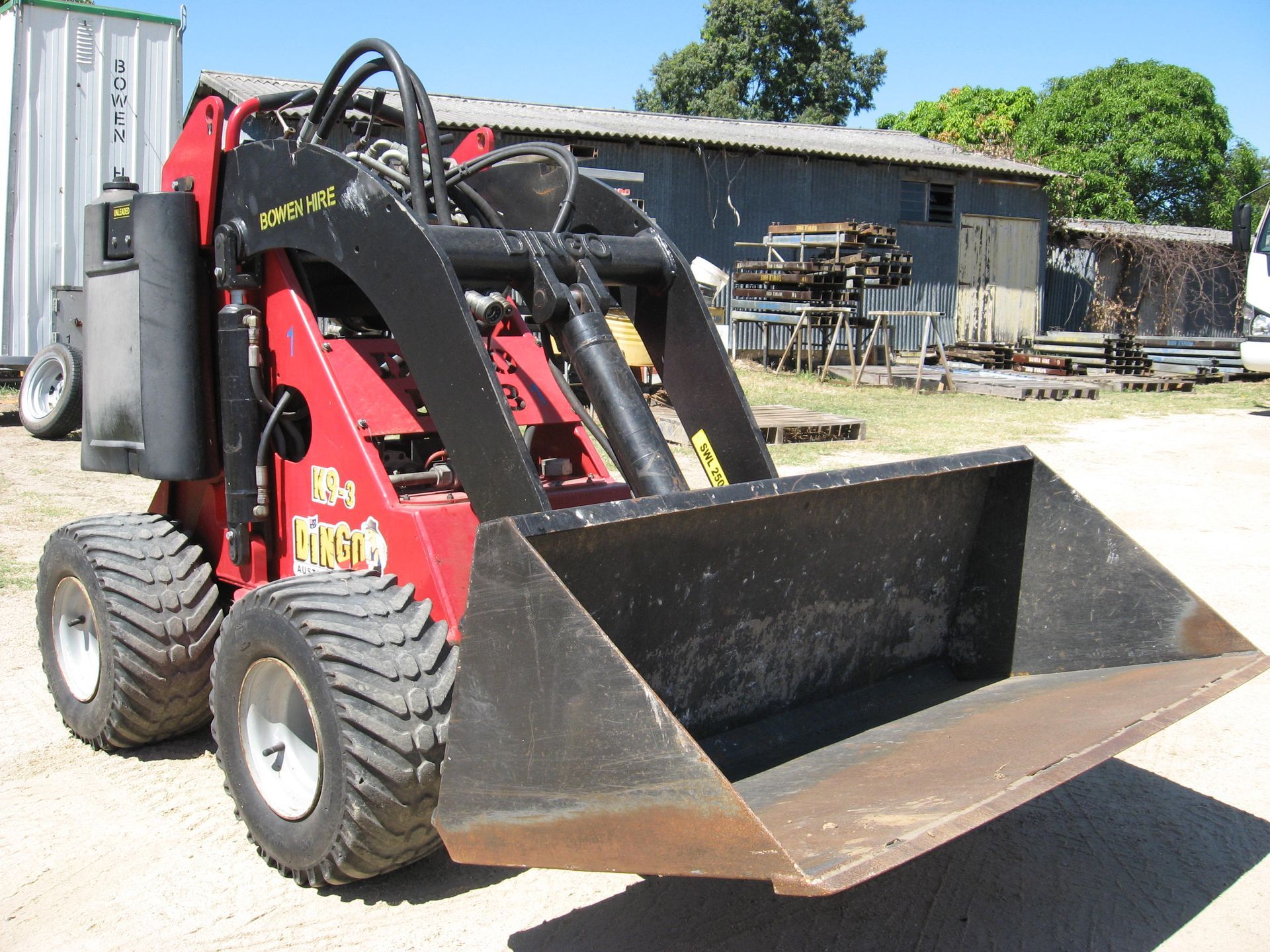 Red Skid Steer Loader with A Front Bucket Parked Outdoors — Bowen Hire in Bowen, QLD