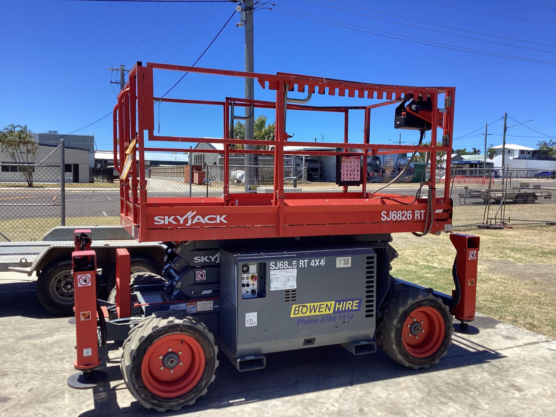 Red Skyjack Scissor Lift Parked Outdoors on a Gravel Lot Under a Clear Blue Sky — Bowen Hire in Bowen, QLD