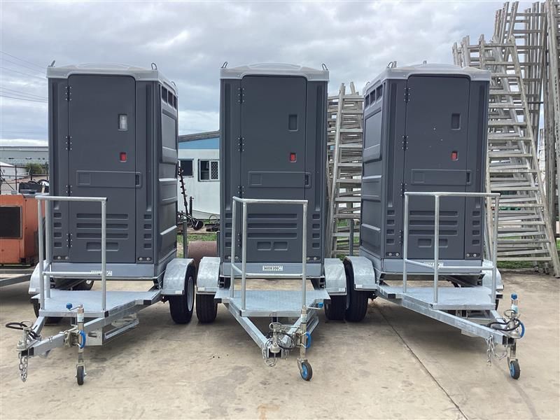 Three gray portable air conditioners on wheeled platforms outdoors near industrial stairs — Bowen Hire in Bowen, QLD