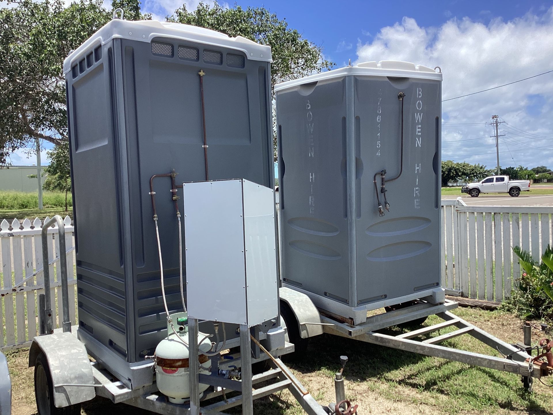 Two Gray Portable Toilets on Trailers in A Fenced Outdoor Lot — Bowen Hire in Airlie Beach, QLD