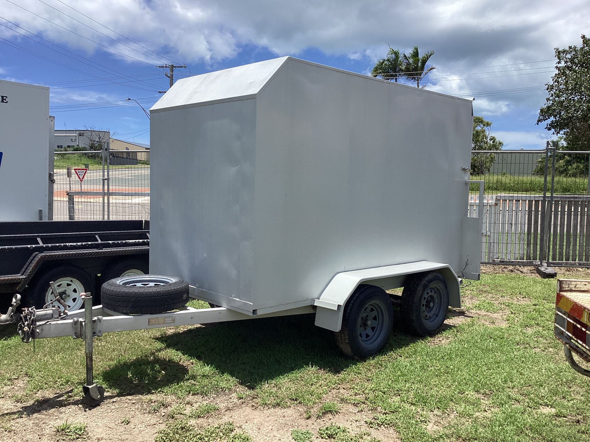 Gray Enclosed Utility Trailer Parked on Grass Under a Partly Cloudy Sky — Bowen Hire in Bowen, QLD