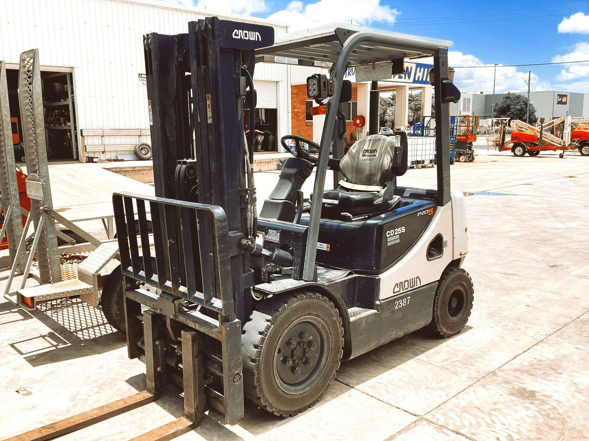 A Dark Blue and White Crown Forklift Parked on a Paved Outdoor Lot During a Sunny Day — Bowen Hire in Bowen, QLD