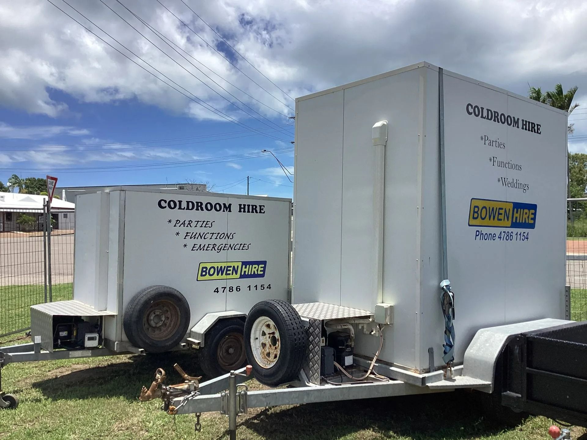 Two White Mobile Coldroom Trailers Parked on a Grassy Lot Under a Sunny Sky — Bowen Hire in Bowen, QLD