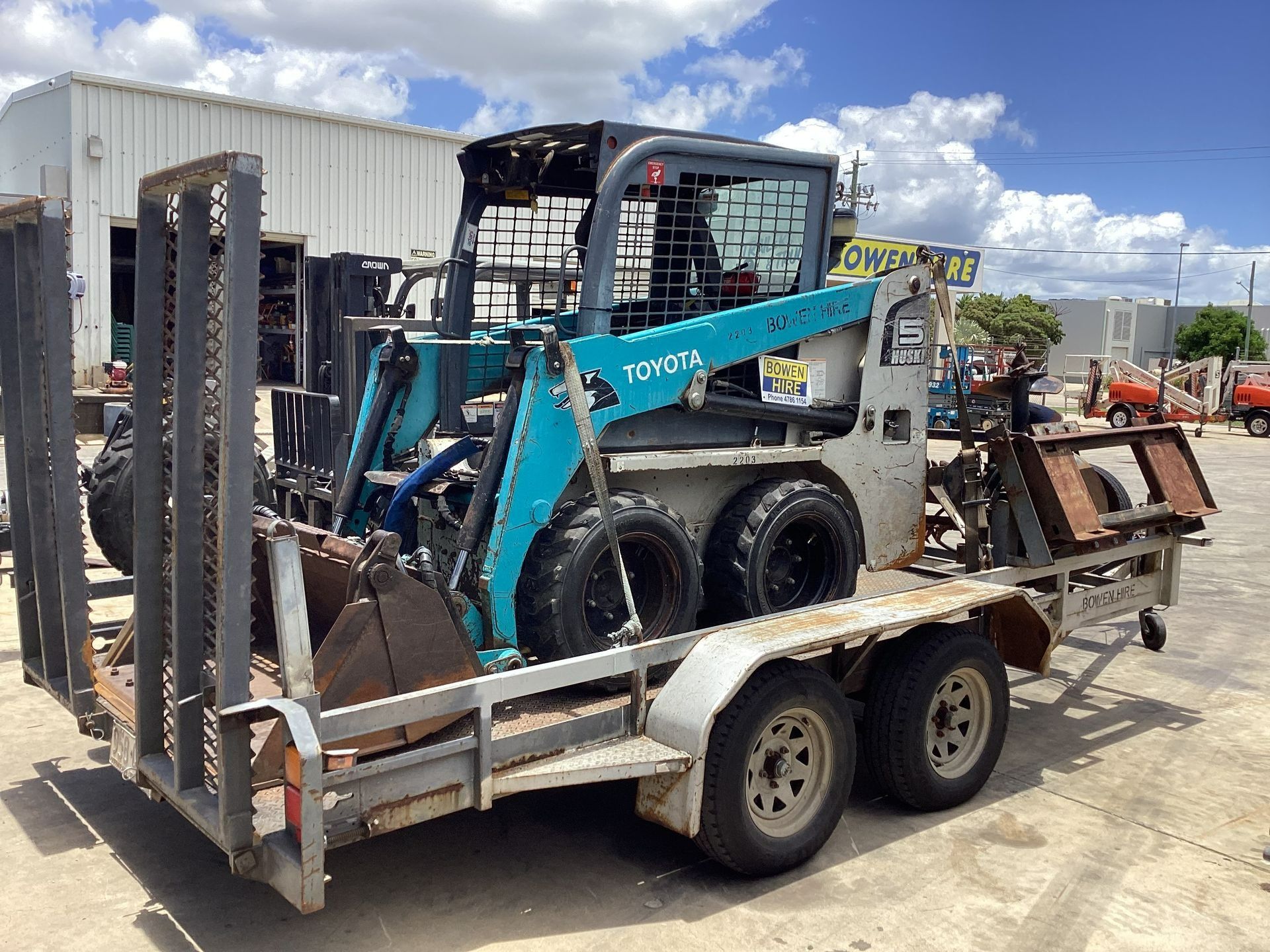 A Teal Toyota Skid Steer Loader Sits on a Flatbed Trailer — Bowen Hire in Bowen, QLD