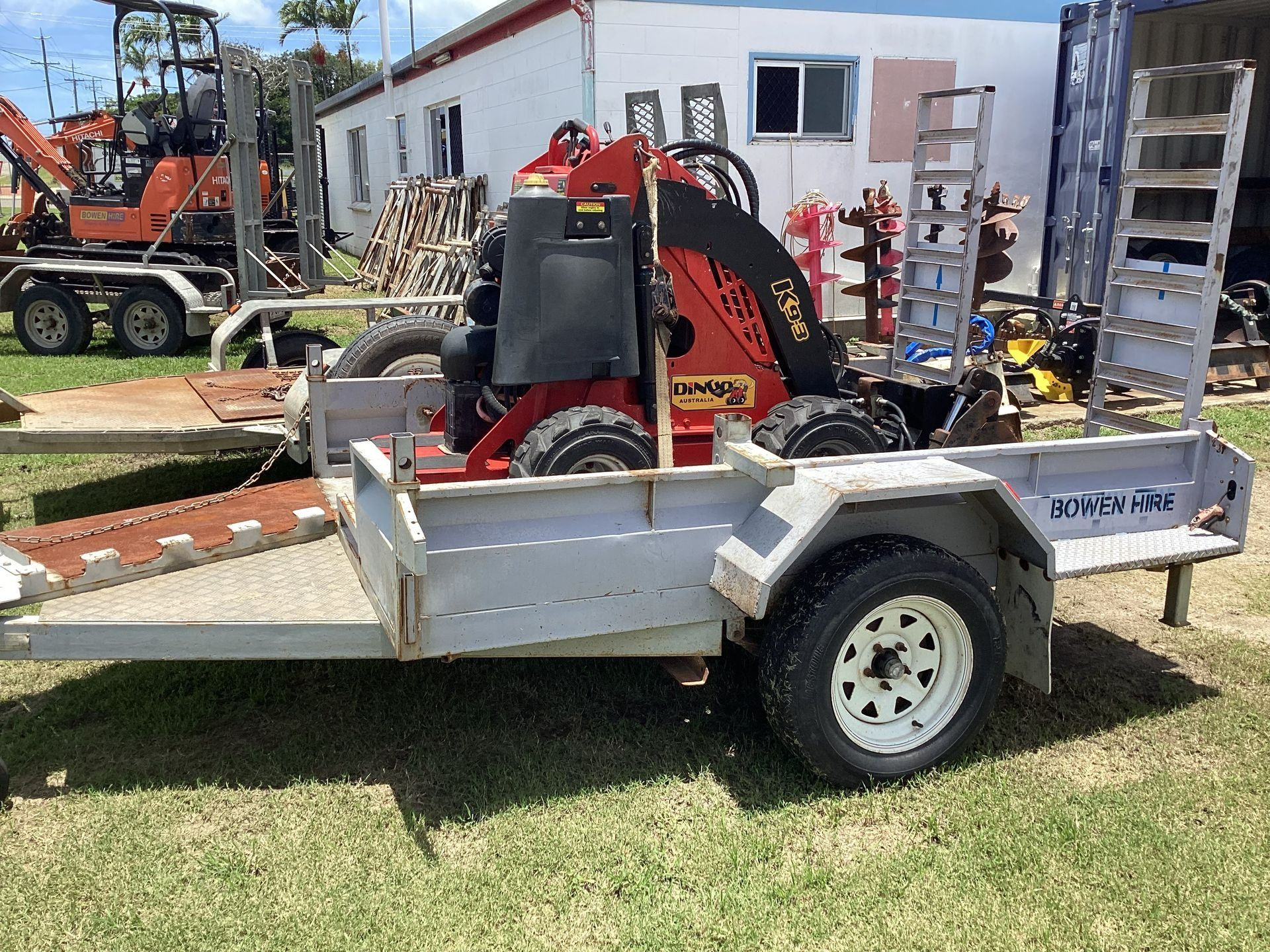 A Red Dingo Mini Skid Steer Loader Sits on a Silver Trailer — Bowen Hire in Bowen, QLD