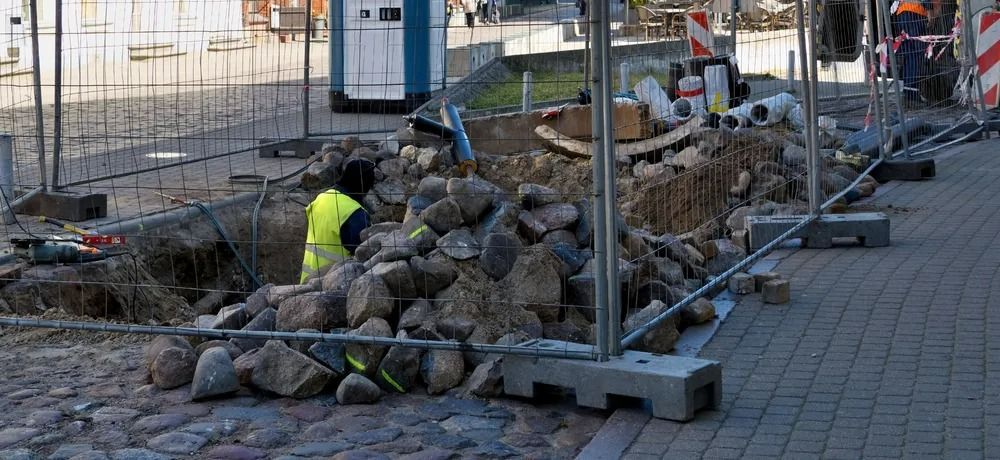 A Worker in a Yellow Safety Vest Digs in a Trench Filled With Rocks — Bowen Hire in Proserpine, QLD