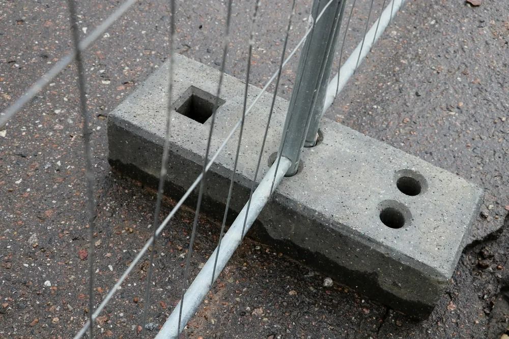 A Grey Concrete Block Acts as a Weighted Base for a Temporary Metal Construction — Bowen Hire in Proserpine, QLD