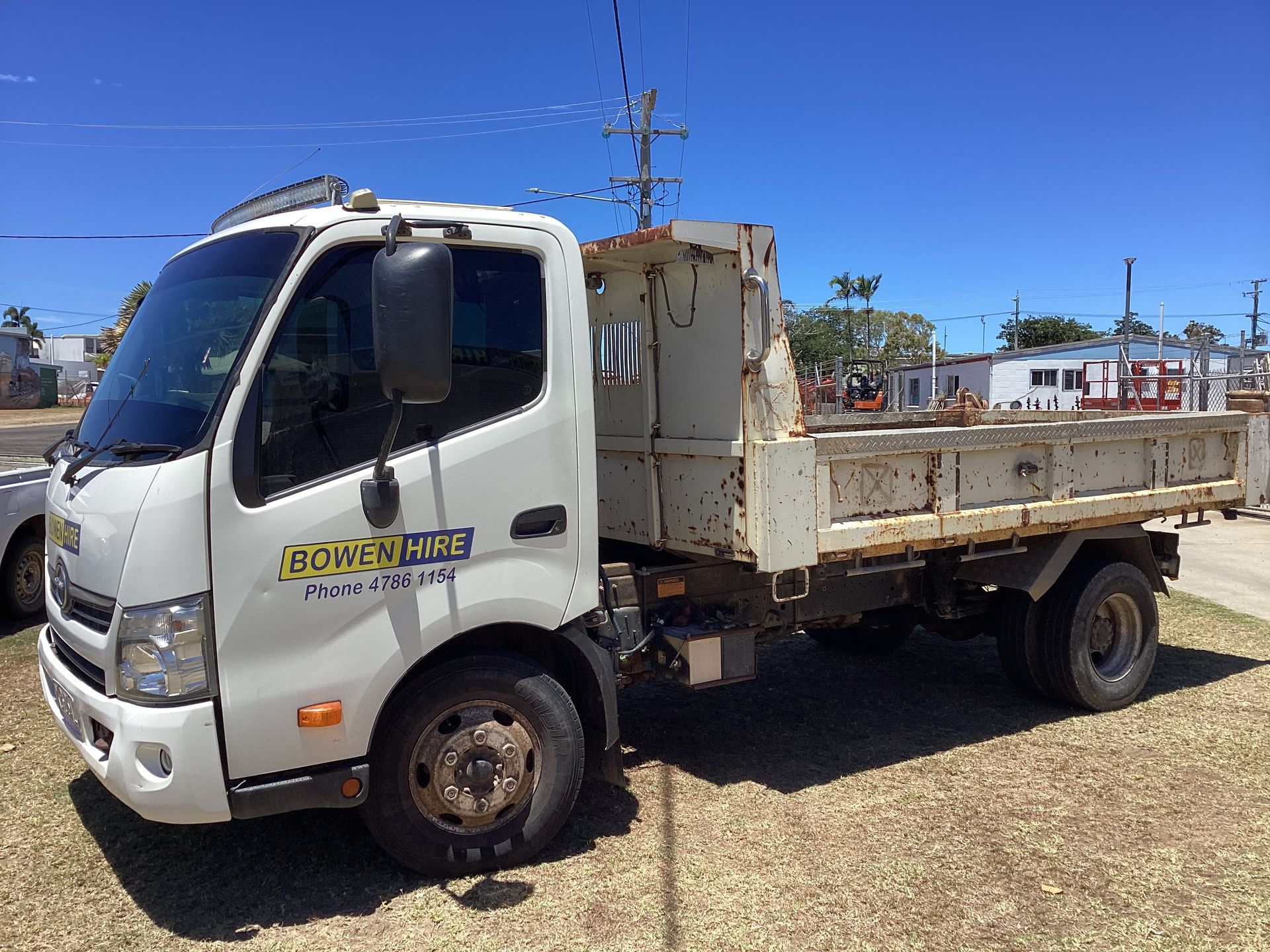 White Flatbed Work Truck Parked on Dirt Under a Clear Blue Sky — Bowen Hire in Bowen, QLD