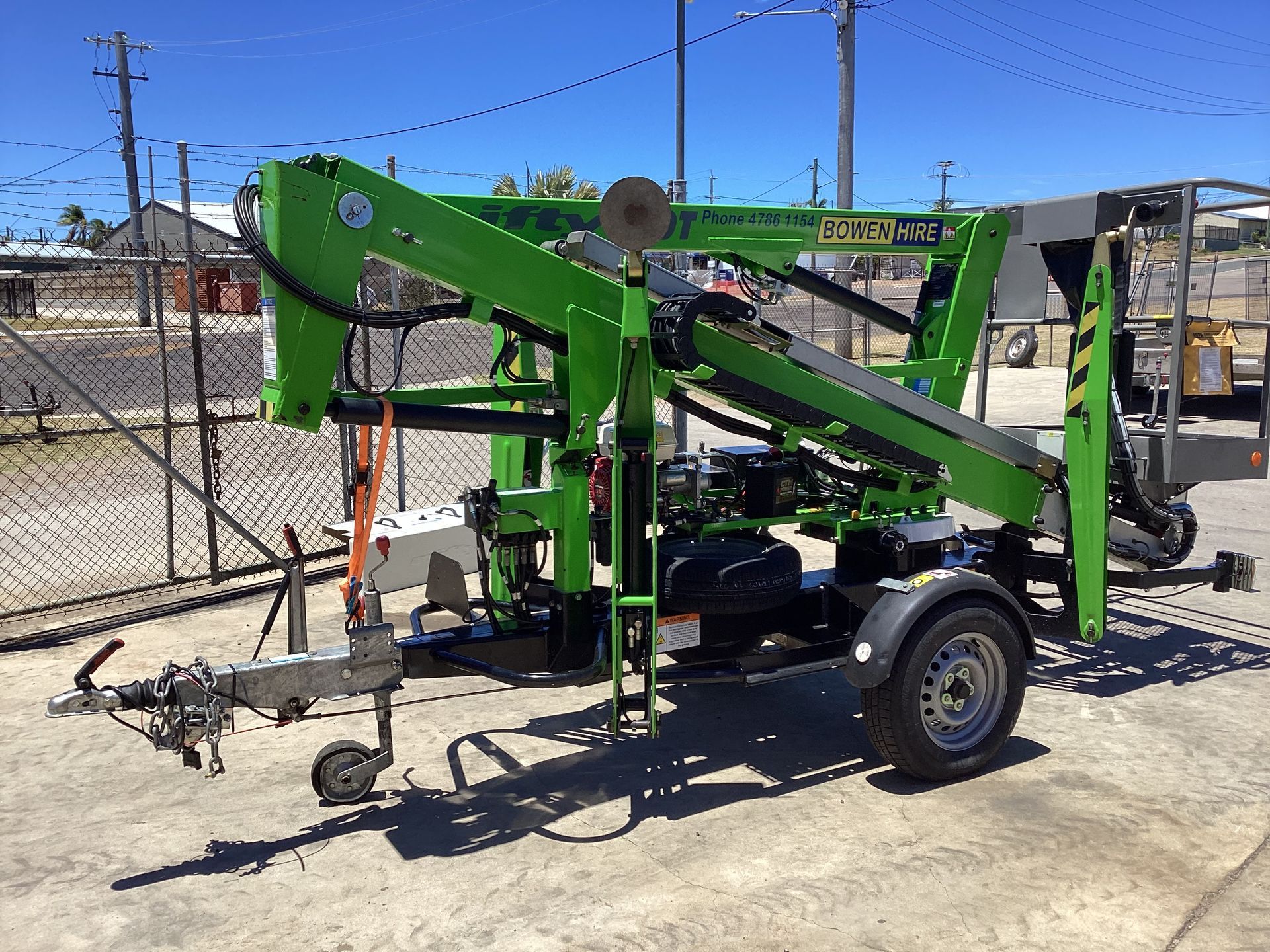 Green Trailer-mounted Hydraulic Boom Lift Parked Outdoors — Bowen Hire in Bowen, QLD
