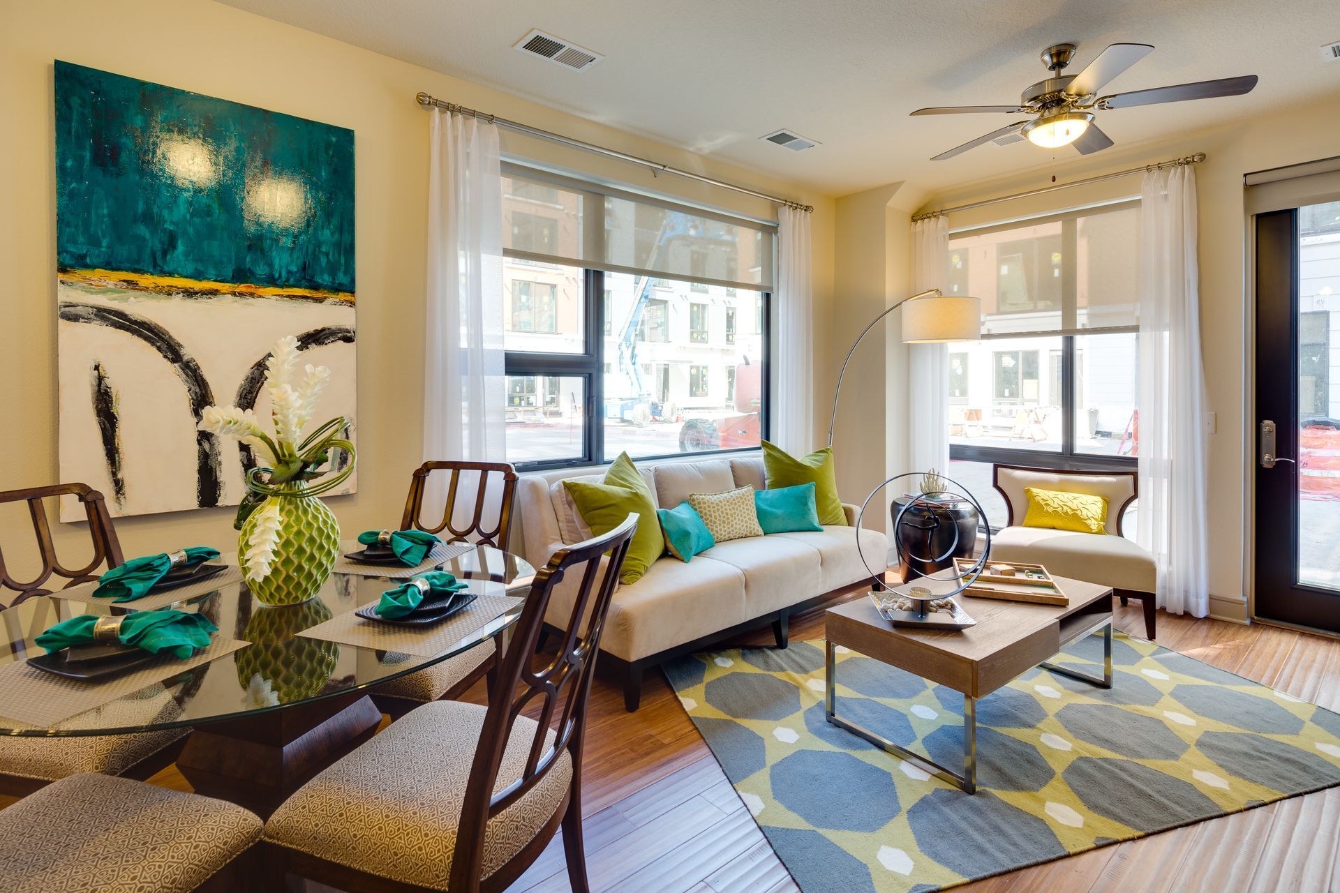 A living room with a couch , table , chairs and a ceiling fan.