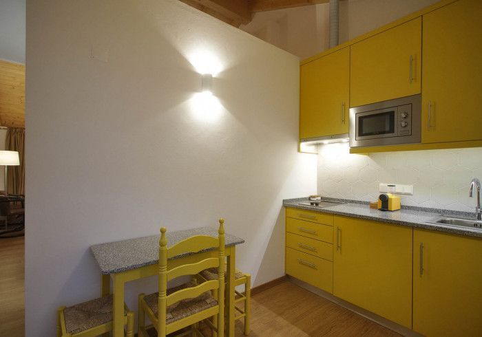 Cozinha amarela com armários combinando, um micro-ondas e uma pequena mesa com cadeiras.