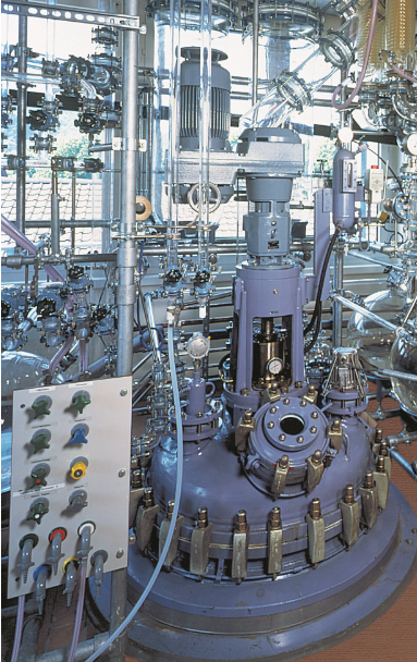 A factory with a lot of stainless steel tanks and pipes.