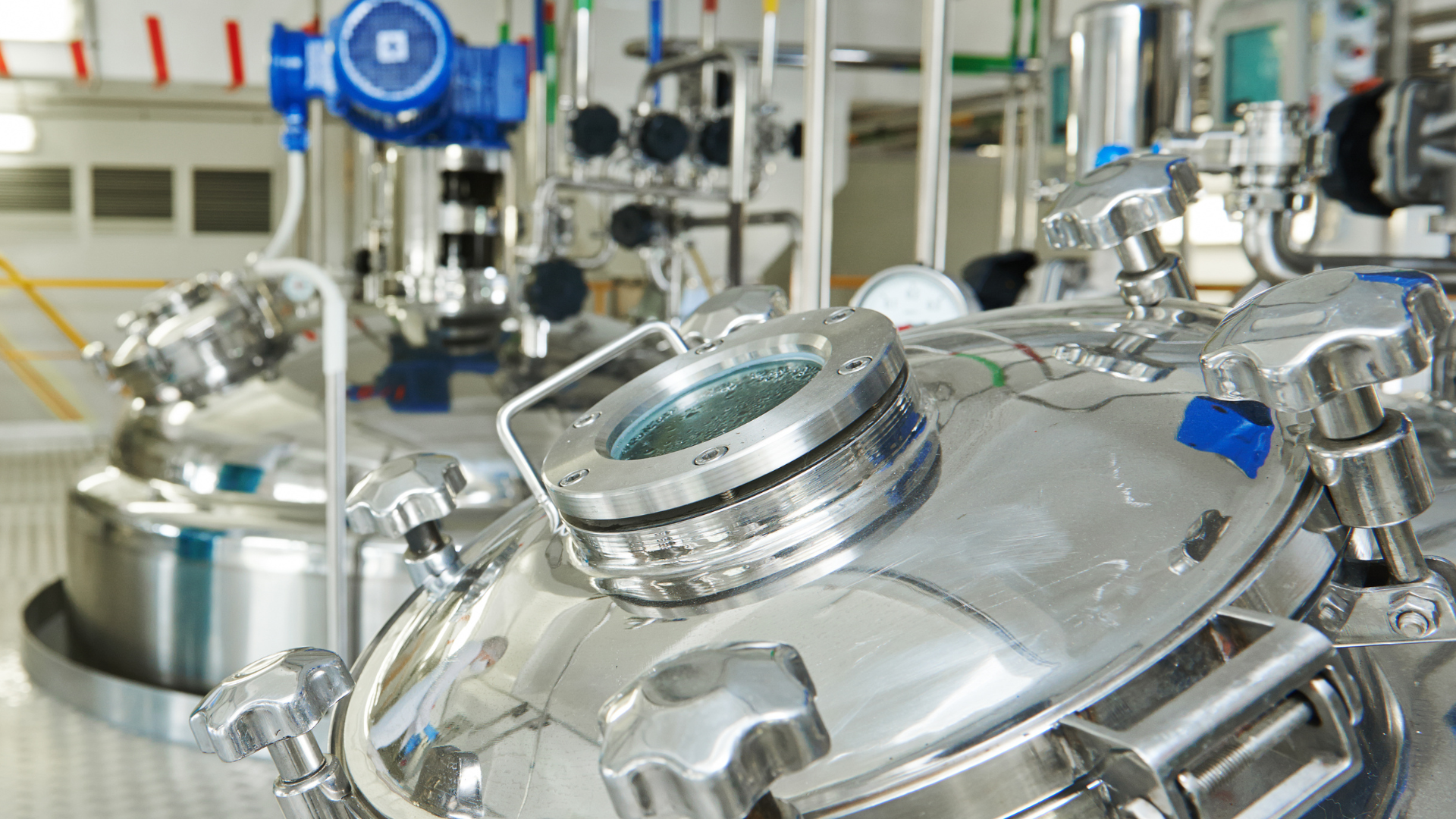 A factory with a lot of stainless steel tanks and pipes.