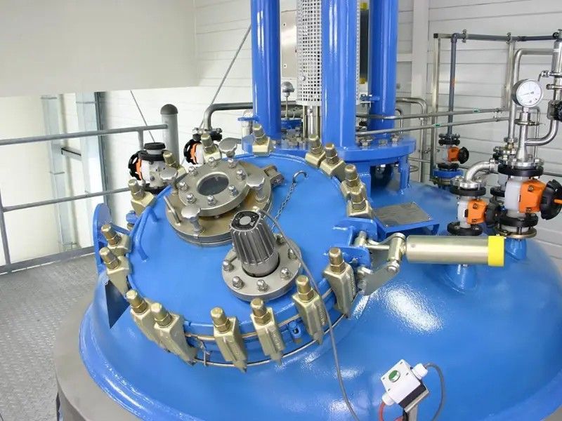 A factory with a lot of stainless steel tanks and pipes.