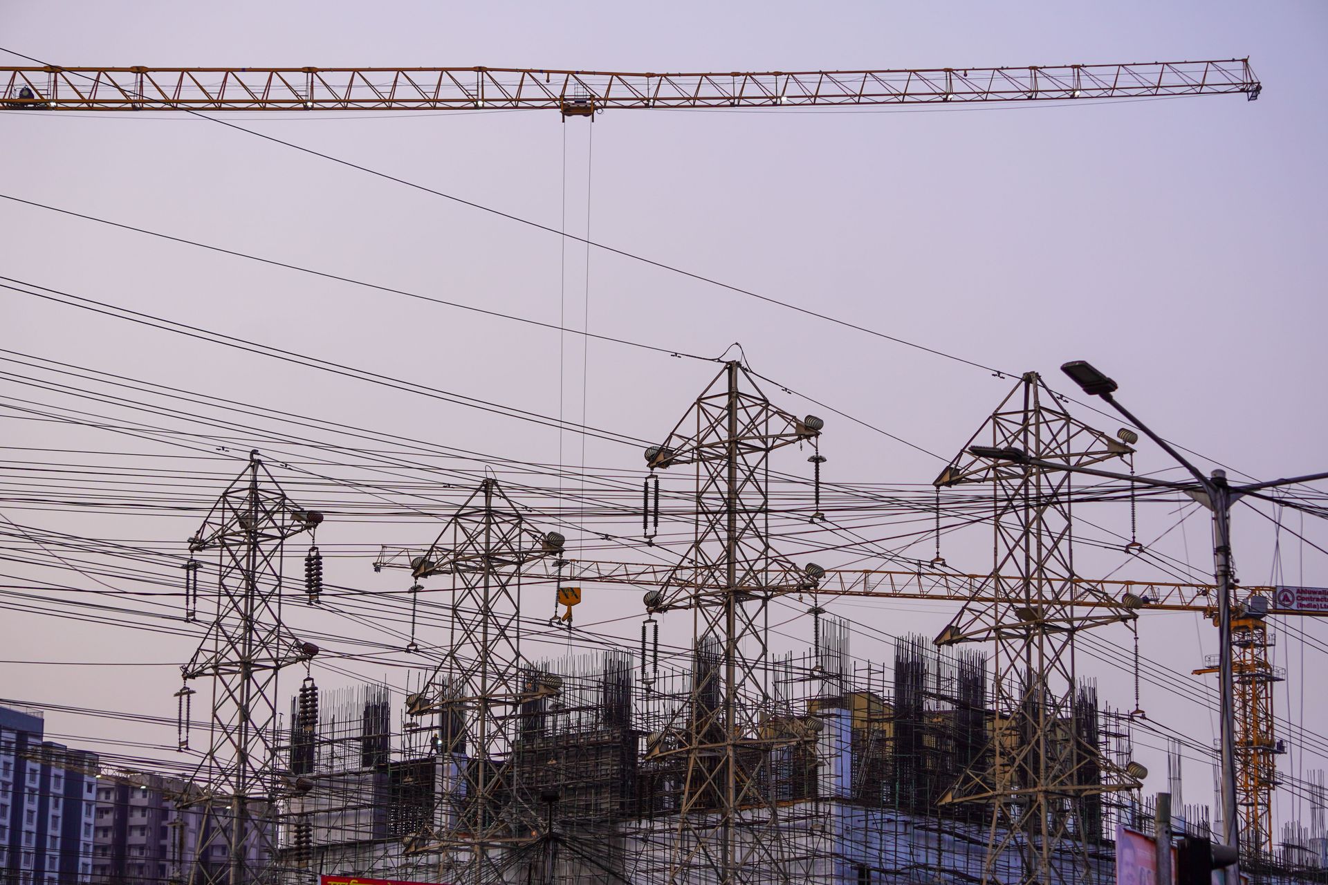 Industrial power station with tall transmission towers and many overhead power lines at dusk
