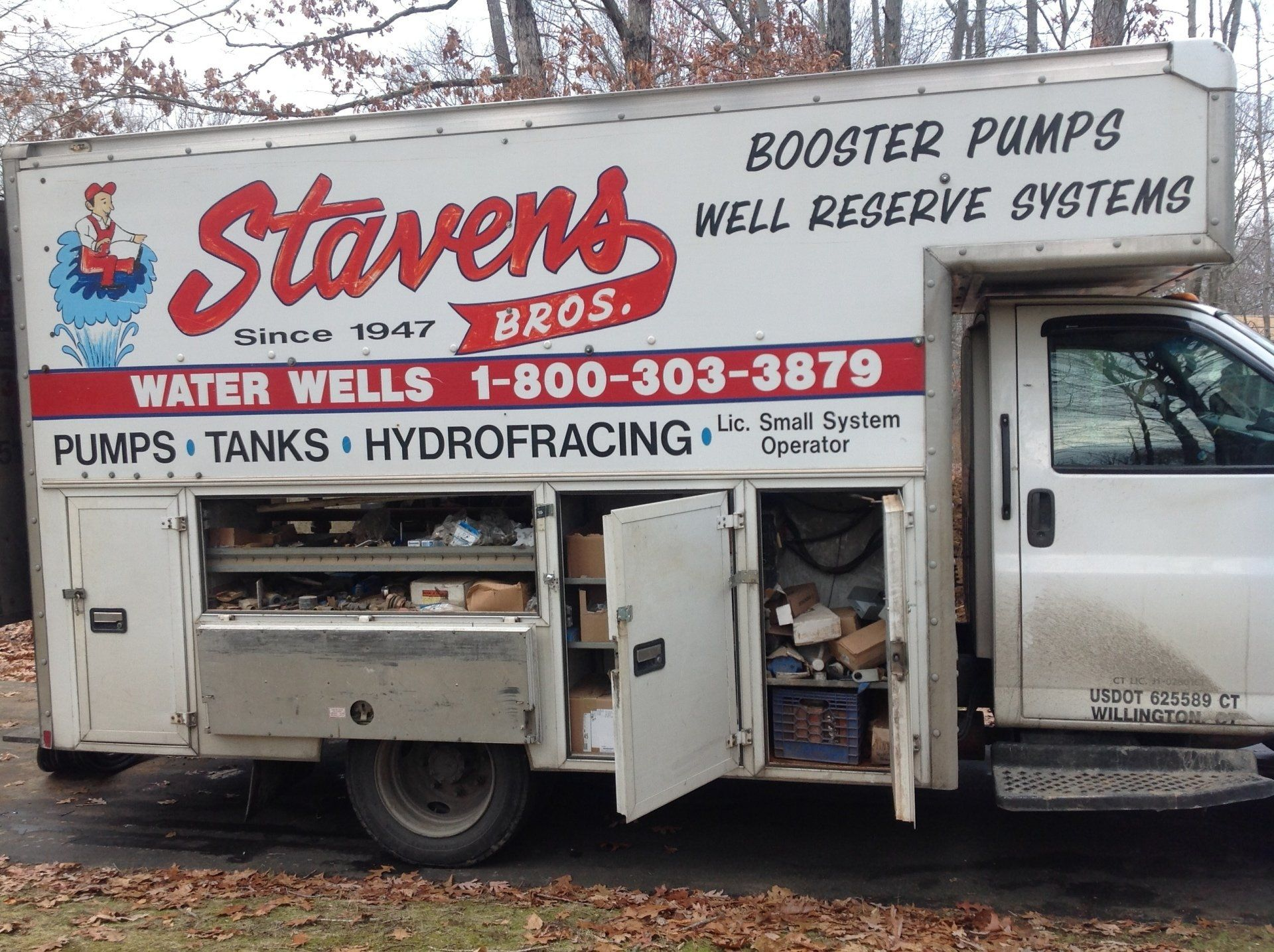 White Stavens Bros. truck with open side compartments, advertising water well services.
