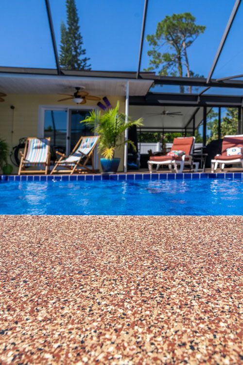 A swimming pool surrounded by chairs and a screened in porch.