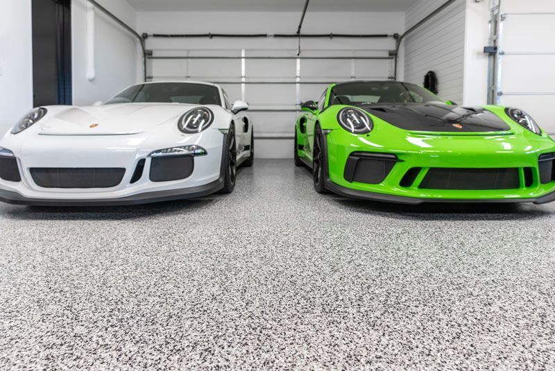 Two sports cars are parked next to each other in a garage.