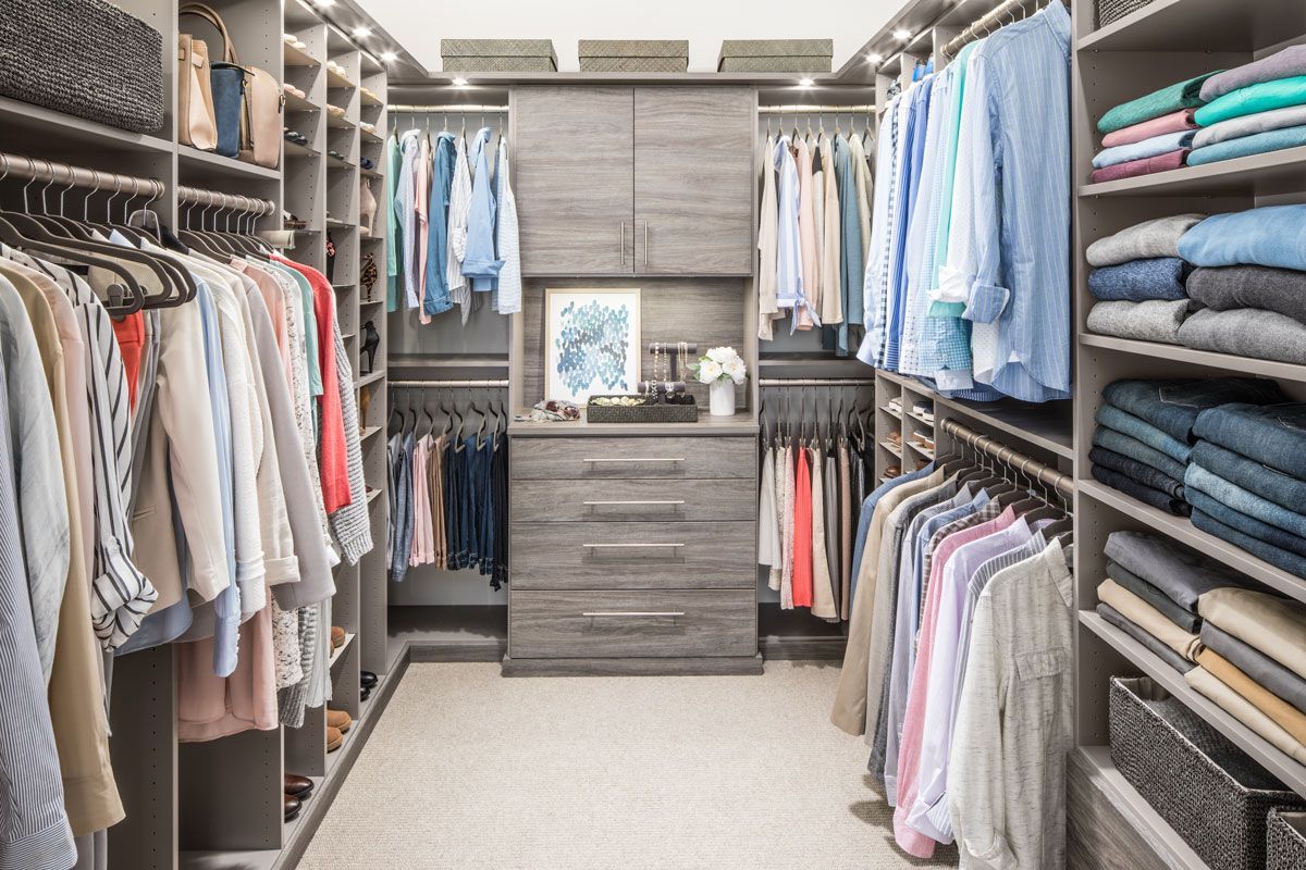 A walk in closet filled with lots of clothes and a dresser.