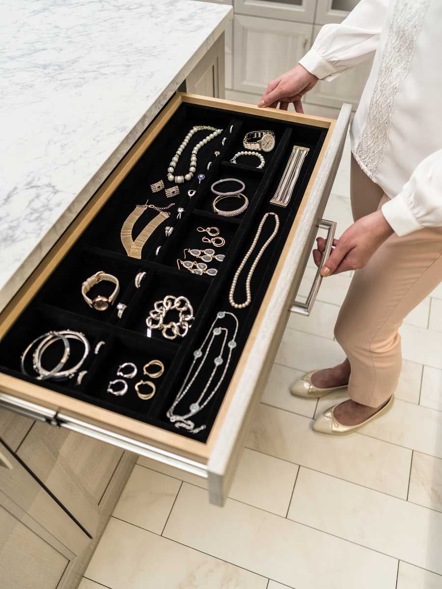 A woman is opening a drawer full of jewelry