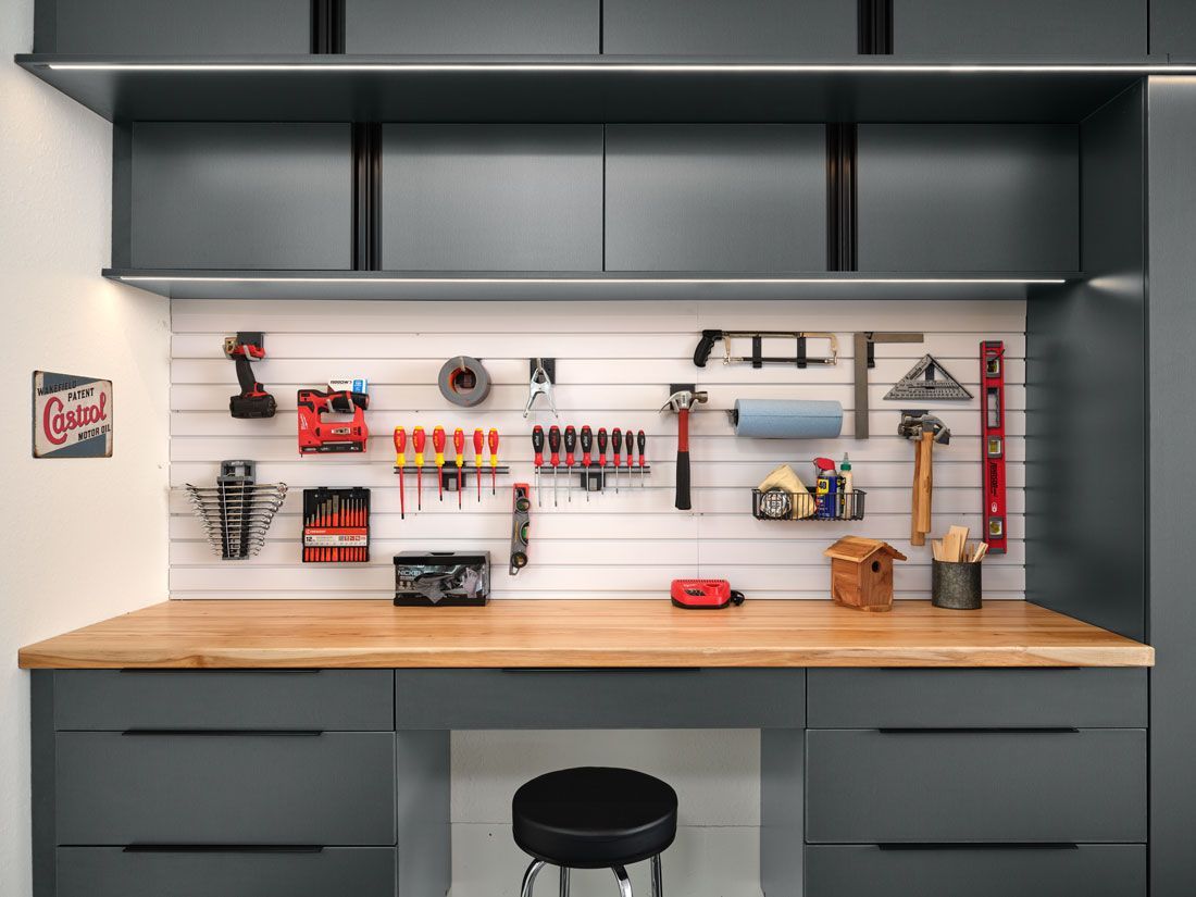A garage with a wooden workbench and a stool.