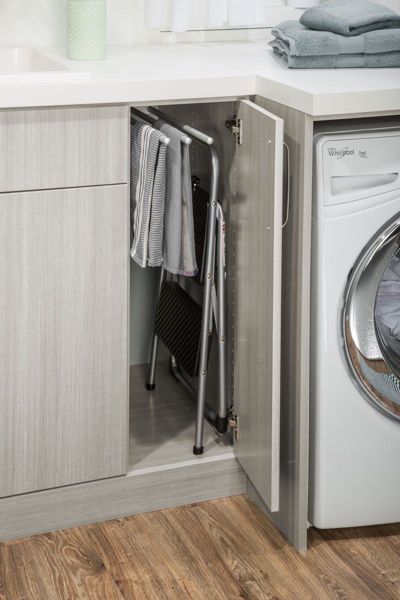A laundry room with a washing machine and a folding chair.