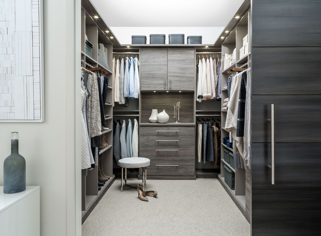 A walk in closet filled with clothes and a stool.