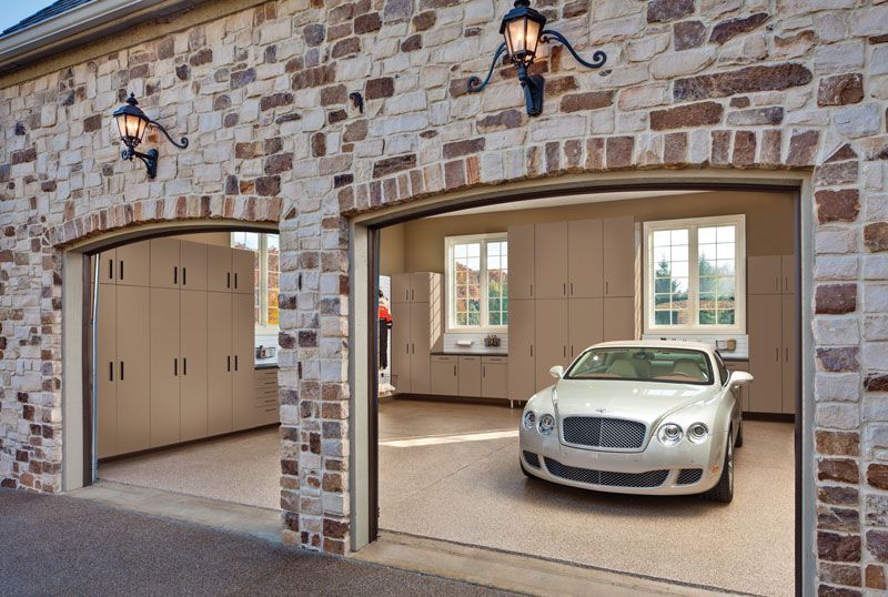 A white car is parked in a garage with the doors open.