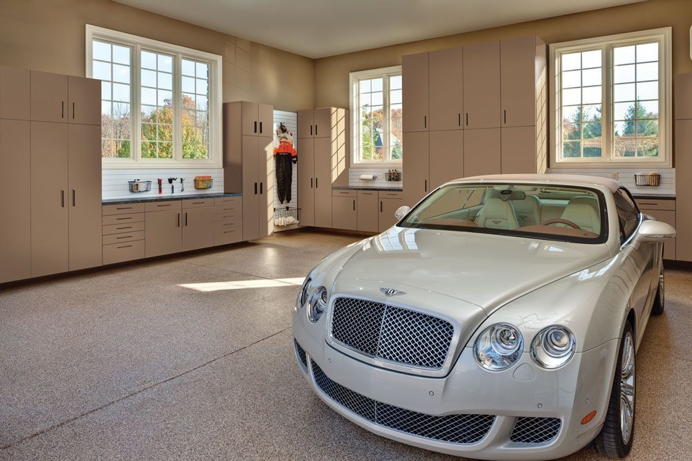A bentley is parked in a garage with lots of cabinets.