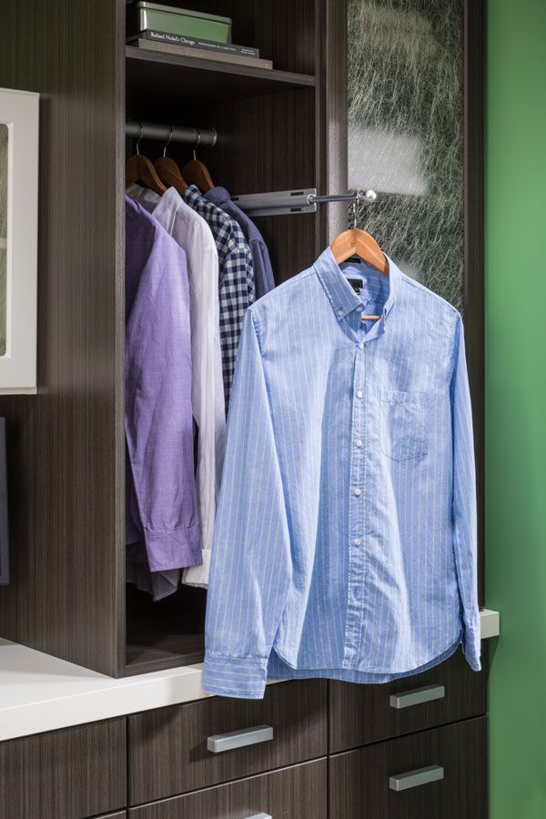 A blue shirt is hanging in a closet with other clothes.