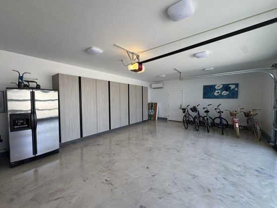 A car is parked in a garage with lots of cabinets.
