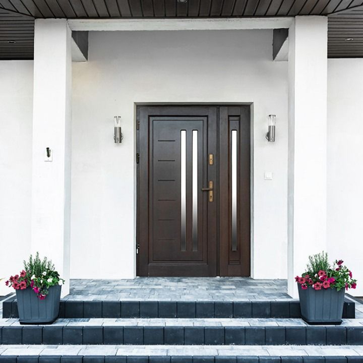 Modern front door with white columns, dark double doors, and potted flowers on the steps