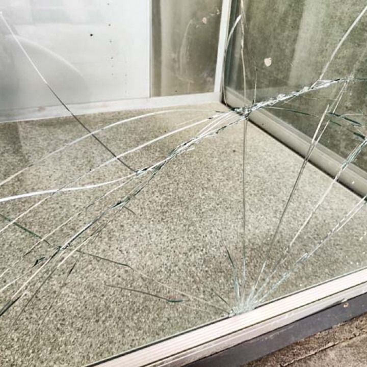 Cracked glass window with shattered pane and broken shards in a metal frame