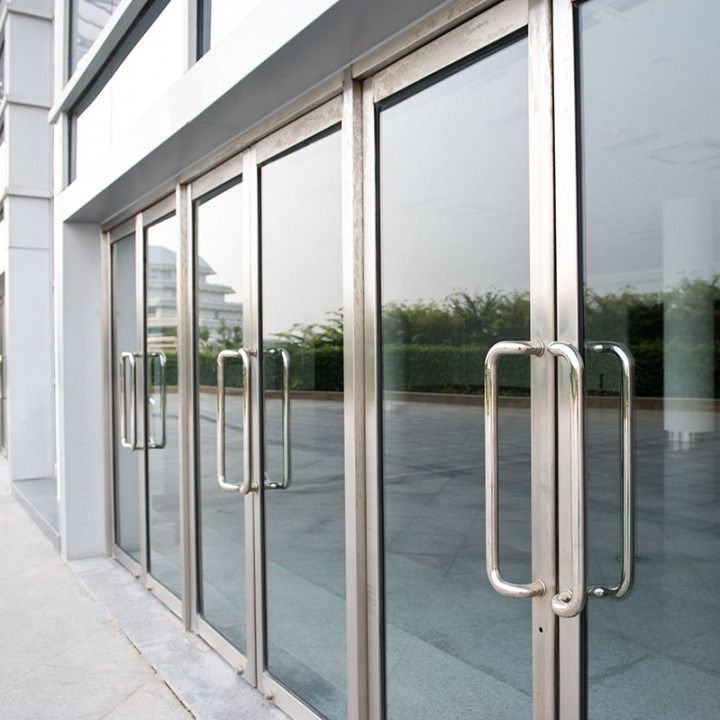 Glass storefront doors with silver handles reflecting an empty outdoor walkway