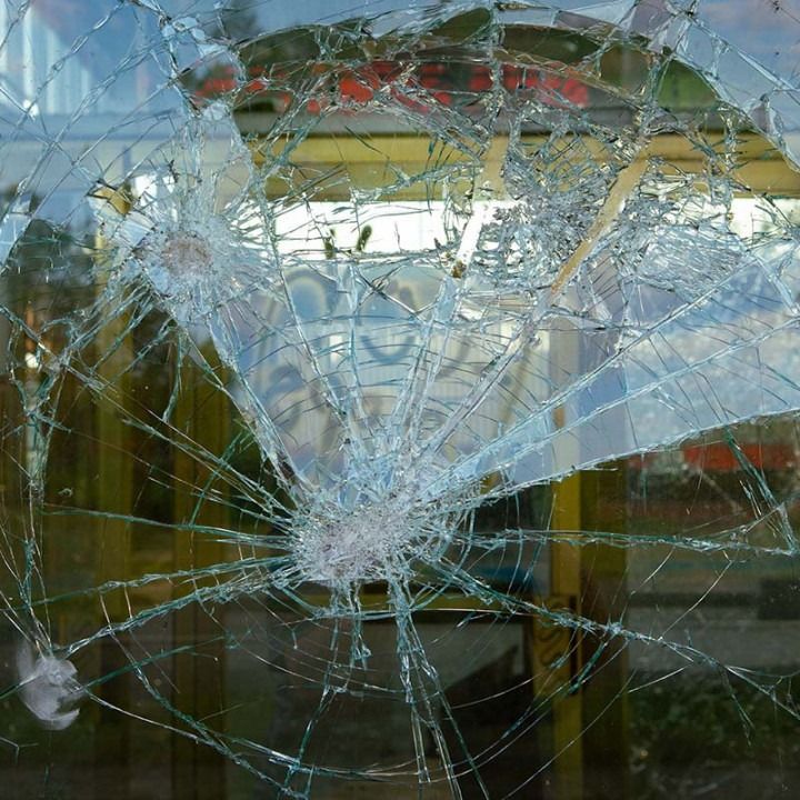 Shattered glass window with a large spiderweb crack and central impact point