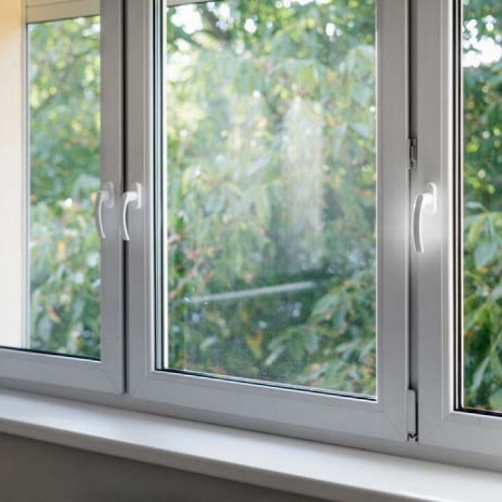 White-framed window overlooking leafy green trees outside.