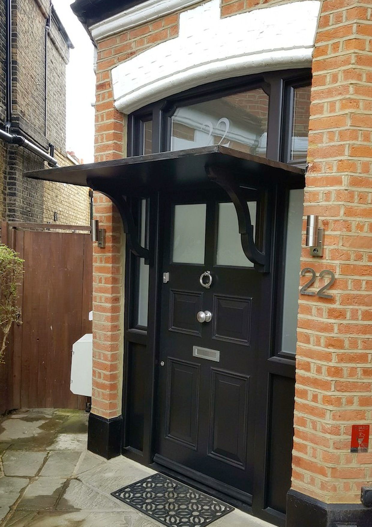A black door with a canopy over it is on a brick building.