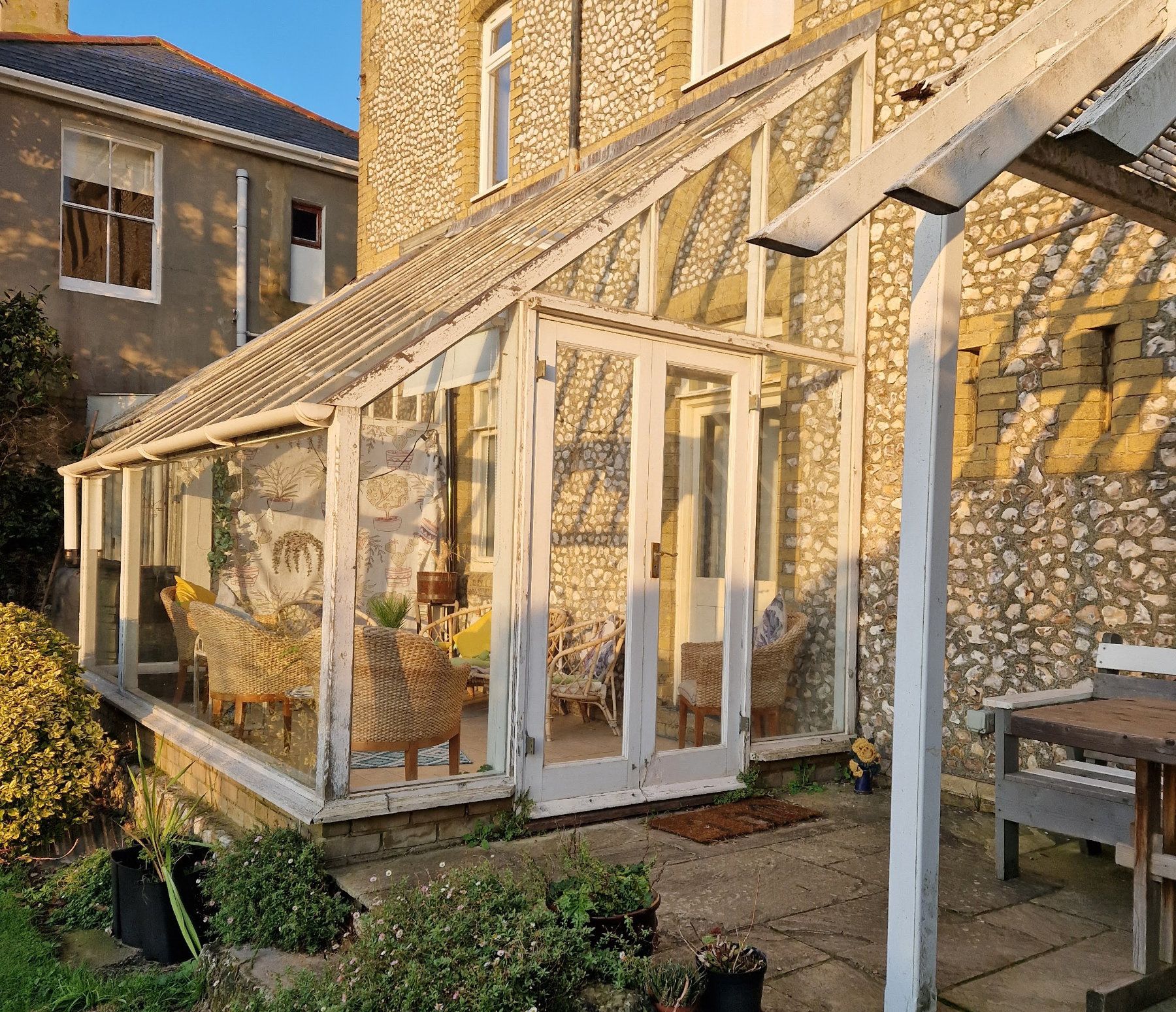 there is a greenhouse in the backyard of a stone building .