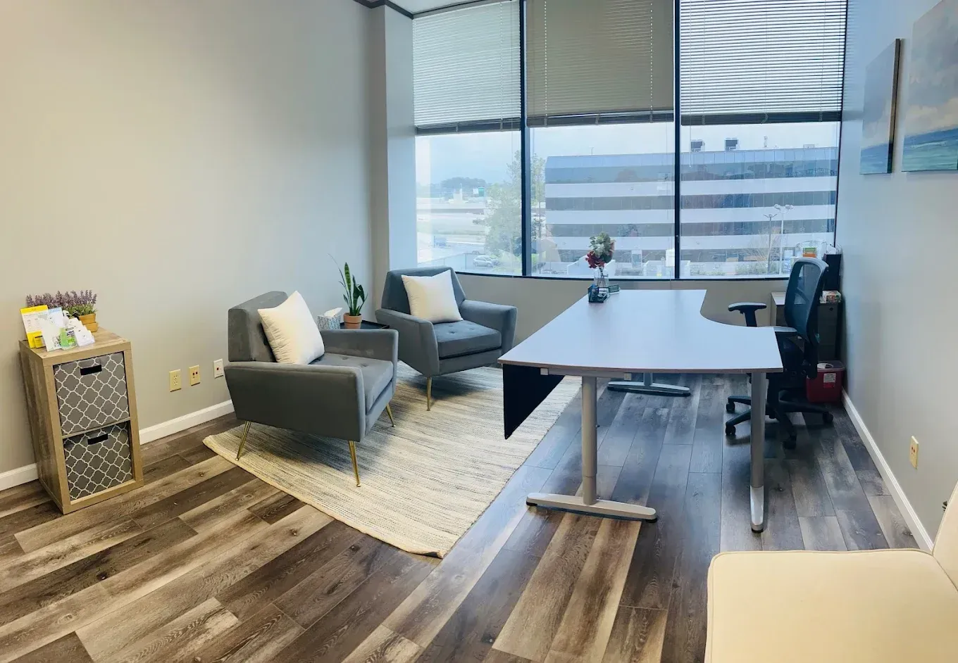 Modern office lounge with chairs, table, rug, and large windows overlooking a city view