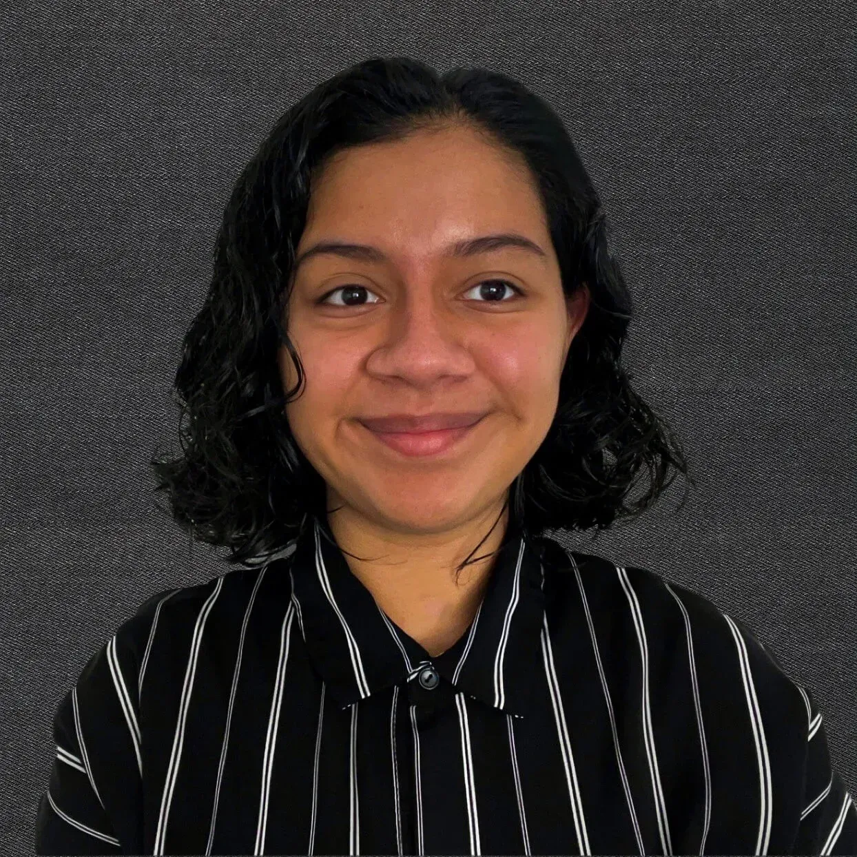 Smiling person in a black striped shirt against a dark textured background.