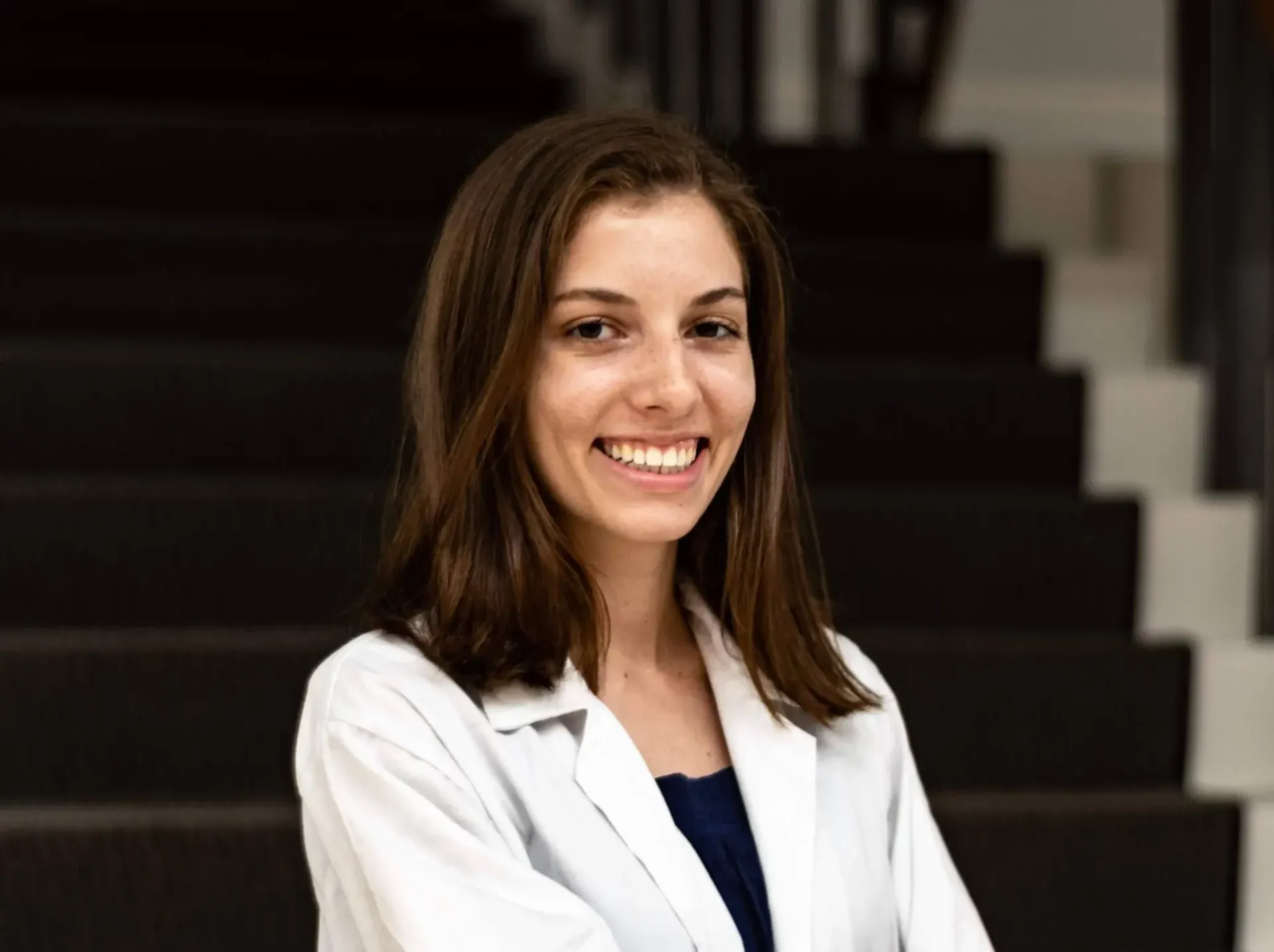 Smiling professional in a white coat standing on stairs