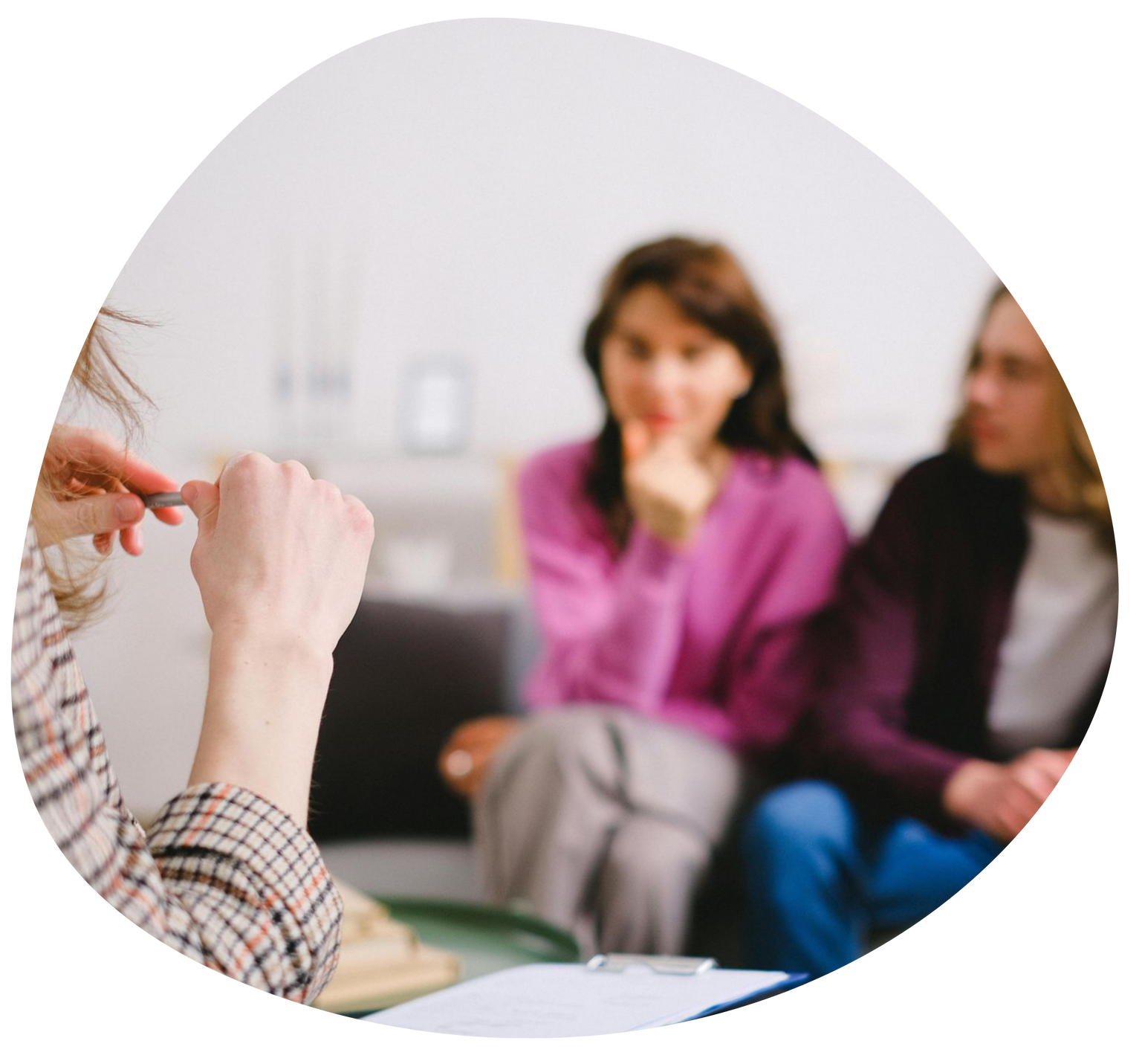 Hands gesturing during a discussion with two people seated in the background