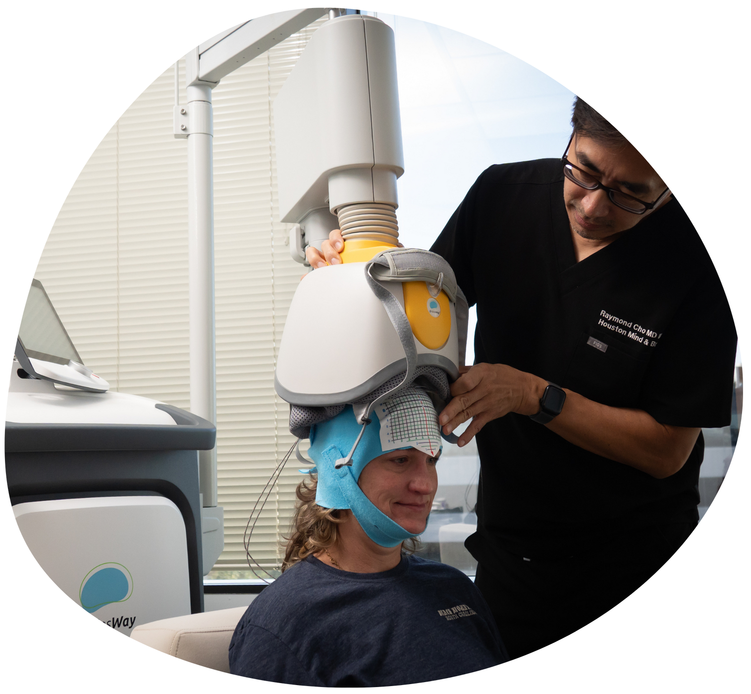 Person wearing a head-mounted device while another adjusts it in a clinical setting