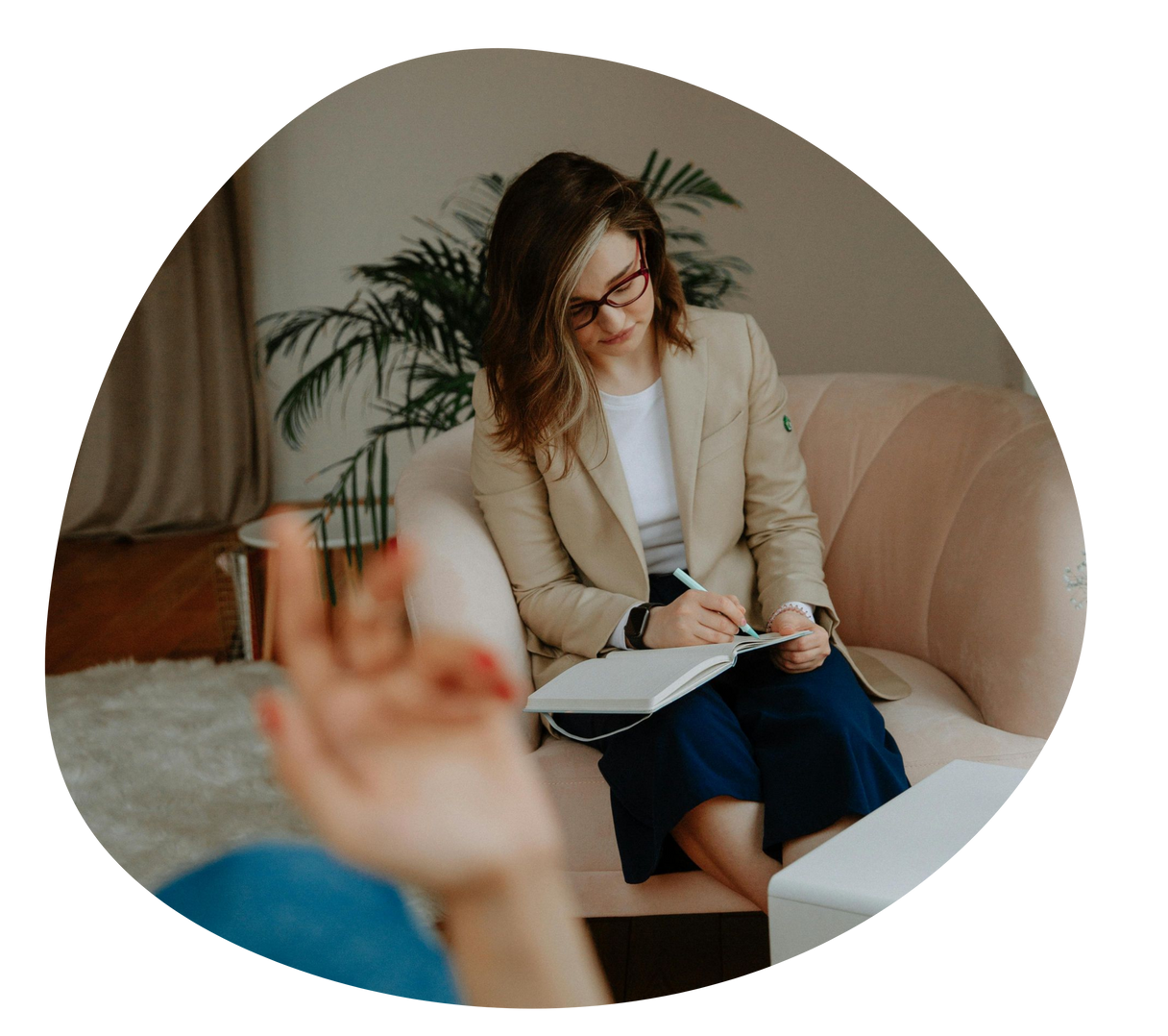 Counselor taking notes during a conversation in a cozy living room-like office